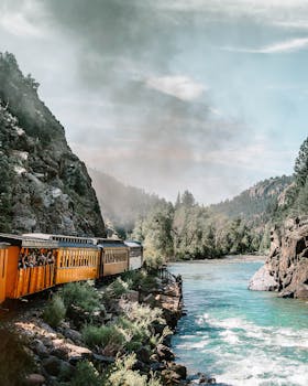 乘坐风景如画的火车，沿着河流穿过郁郁葱葱的山脉，捕捉大自然的美丽