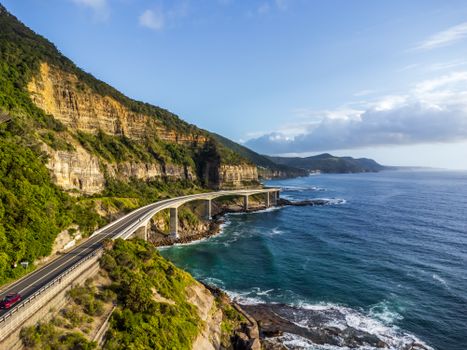 Aerial view of Sea Cliff Bridge curving along the Australian coast with ocean and cliffs.
