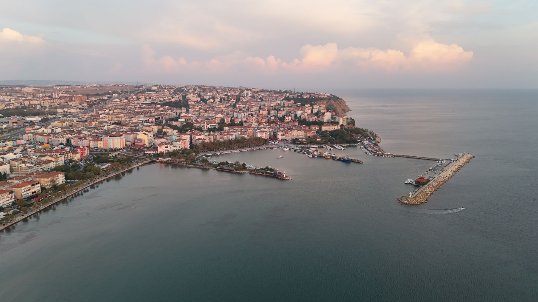 Aerial view of a coastal city and harbour at dusk — photo by bulutlarınaltından on Pexels
