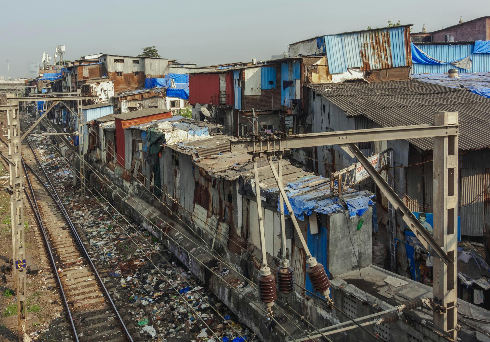 Aerial view of a densely populated slum area alongside railway tracks in Mumbai, India.