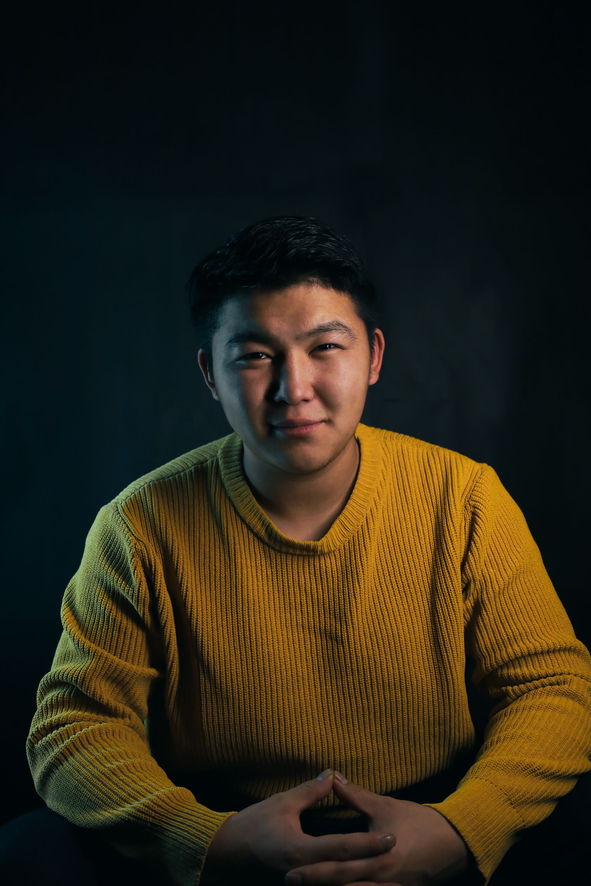 Thoughtful portrait of a person in a cozy yellow sweater, neutral background.