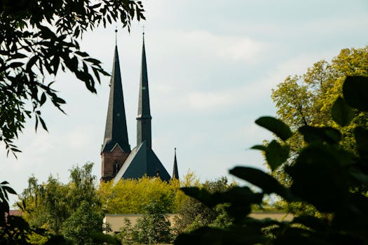 一座历史悠久的教堂，高耸的尖塔矗立在郁郁葱葱的绿植之中