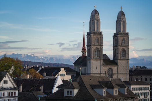 Capture of Grossmünster Church with Swiss Alps in Zurich during daytime.