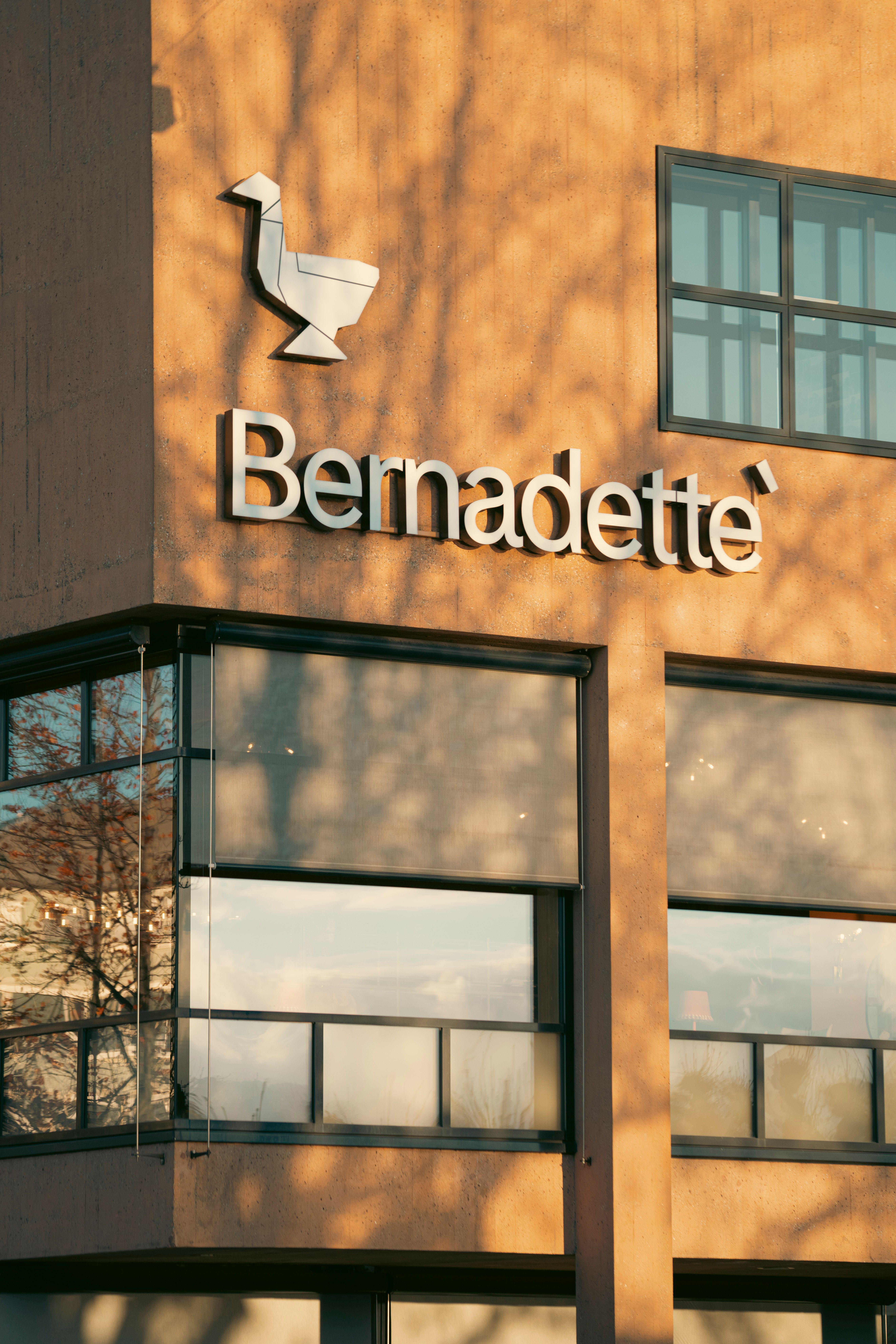 Exterior of a modern building with Bernadette logo and windows during daytime.