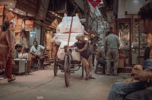 Man Pushing  Goods on a three wheel bike in New Delhi