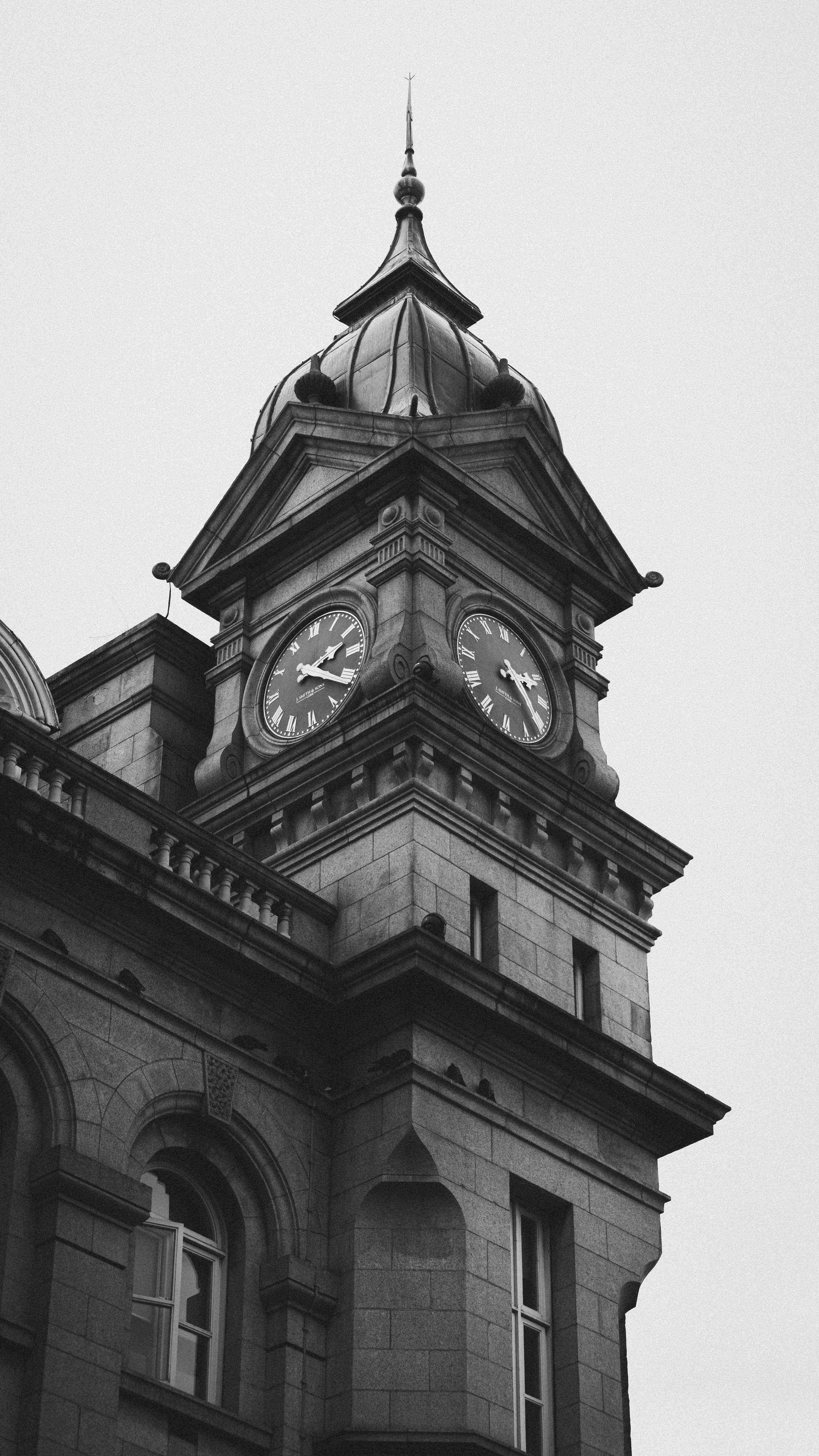 A black and white image of an ornate historic clock tower with intricate architecture.