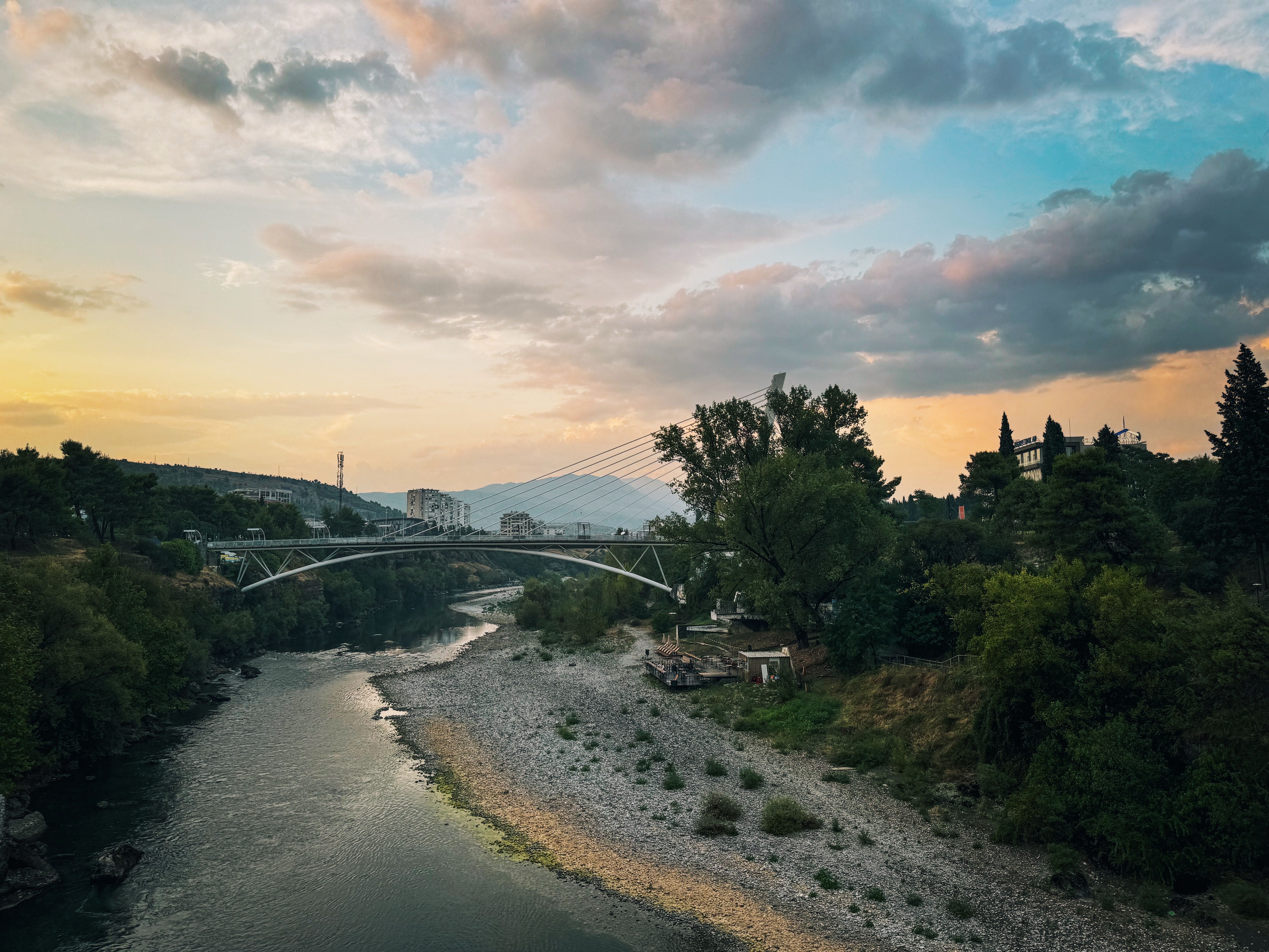 Beautiful sunset over Millennium Bridge in Montenegro with lush greenery and river.