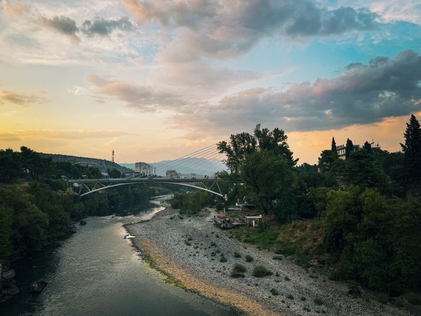 Beautiful sunset over Millennium Bridge in Montenegro with lush greenery and river.