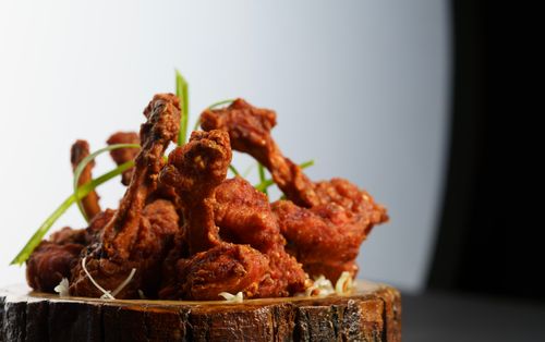 Free Deliciously crispy fried chicken wings served on a rustic wooden plate garnished with green onions. Stock Photo