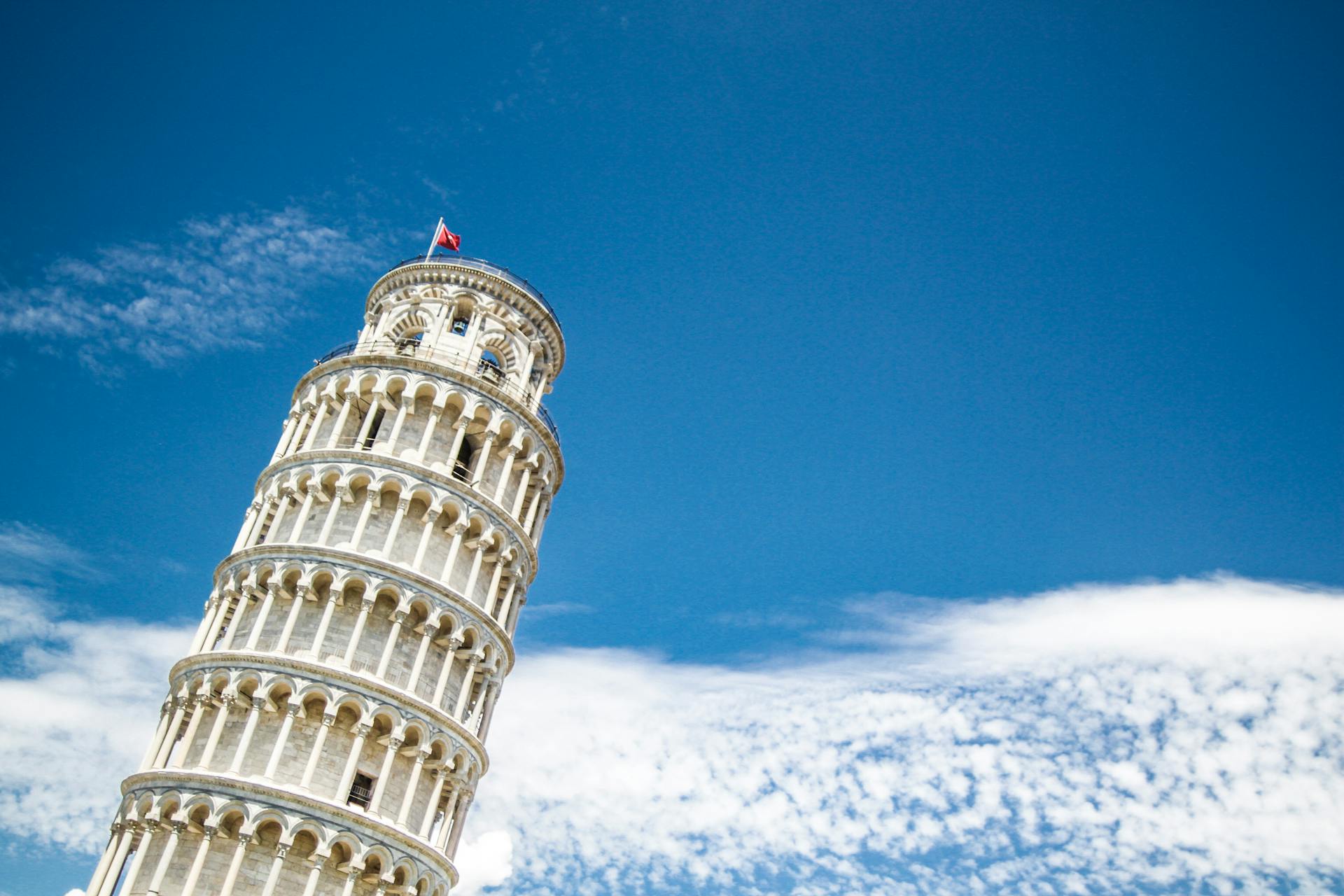 View of the iconic Leaning Tower of Pisa, Italy against a vibrant blue sky, highlighting its architectural elegance.