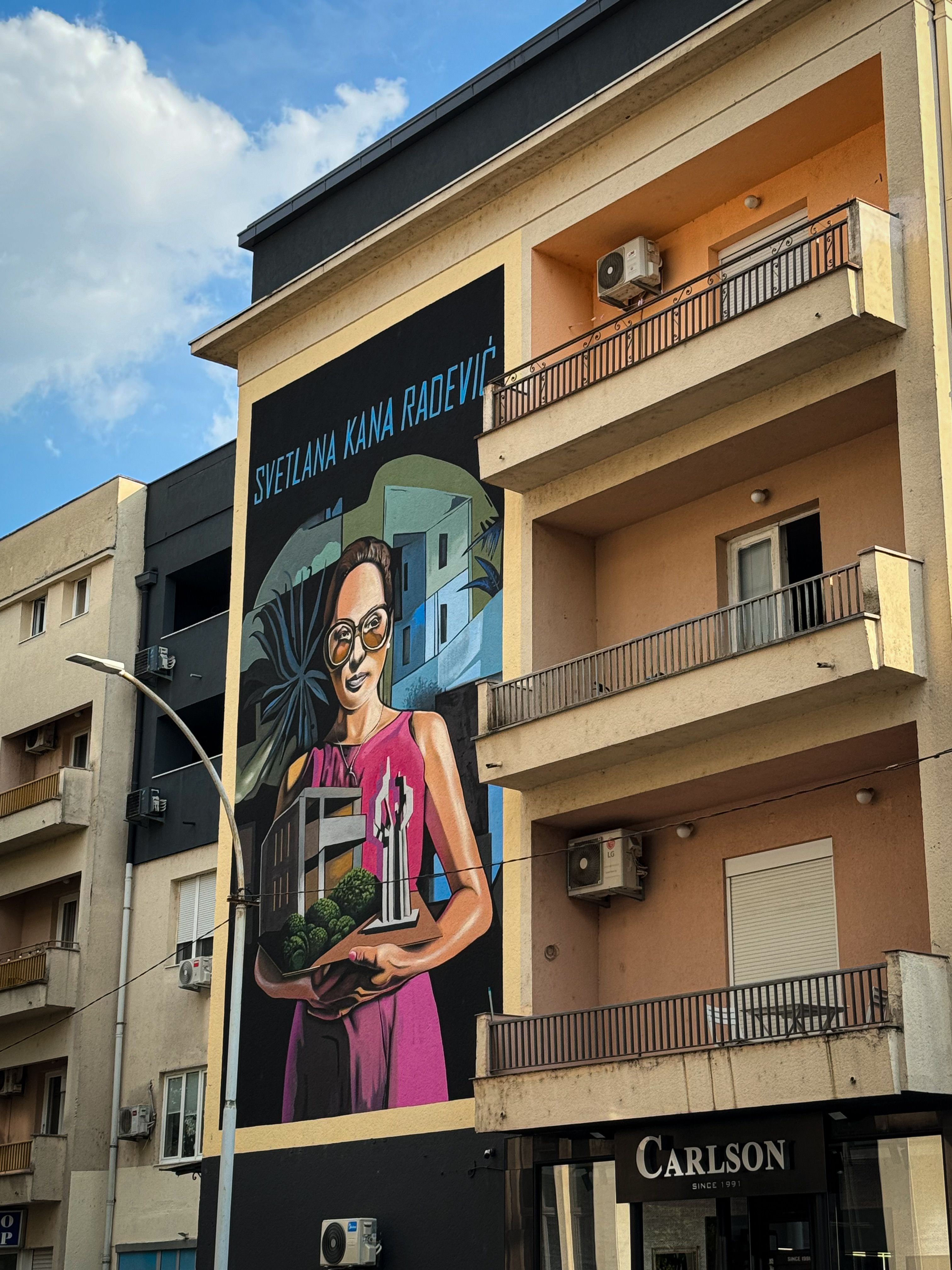 Colorful mural of Svetlana Kana Radević on an urban building's facade.