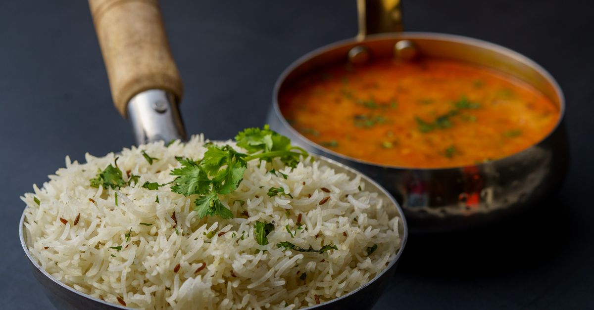 Um prato saboroso de dal indiano com arroz aromático guarnecido com coentro fresco, servido em utensílios tradicionais.