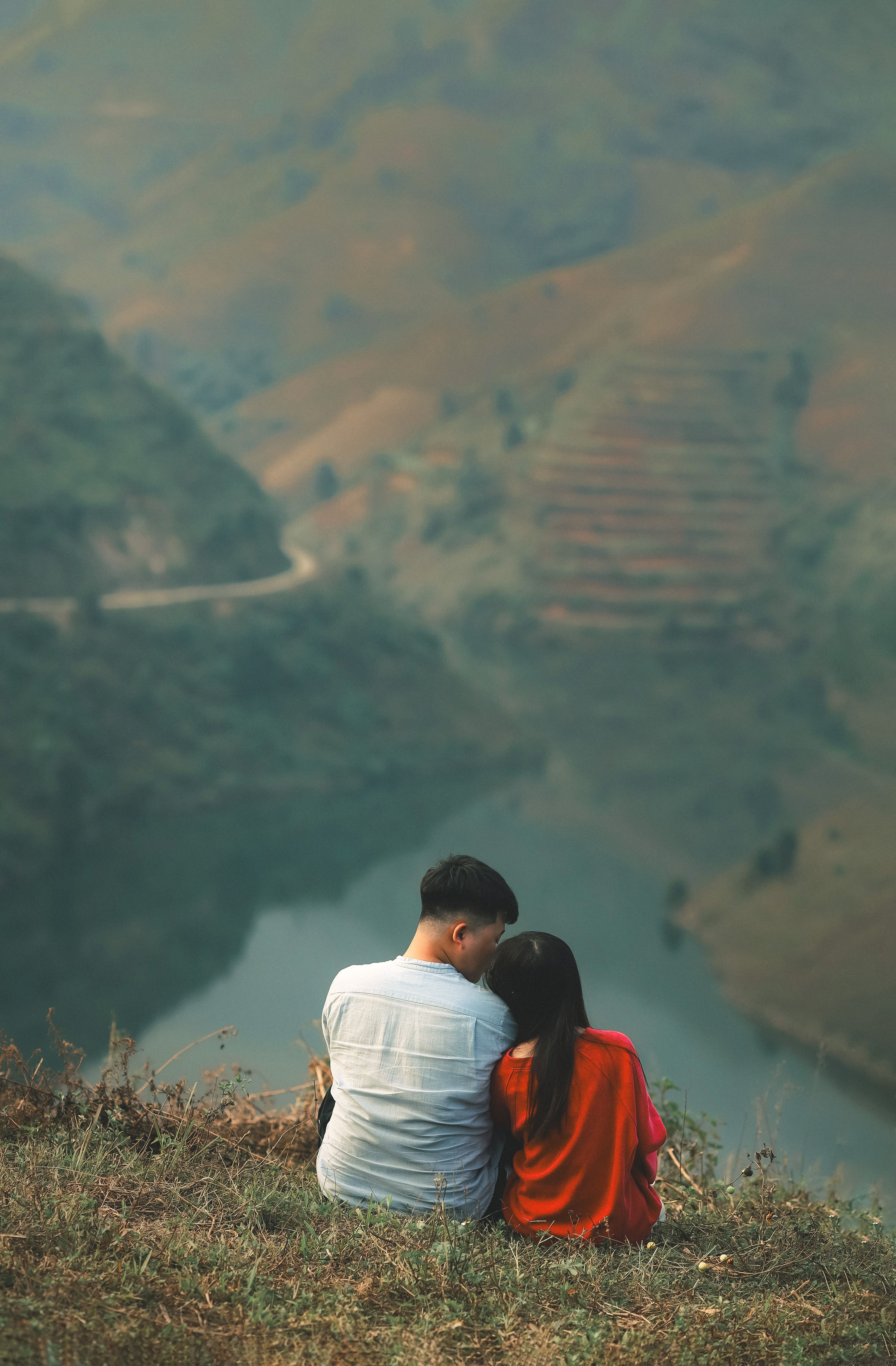 Couple sitting on hill enjoying the scenic mountain landscape of Sơn La, Vietnam.