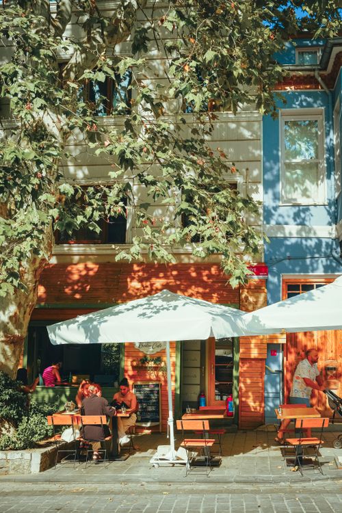 Free Cozy outdoor cafe under trees with patrons enjoying a sunny autumn day. Stock Photo