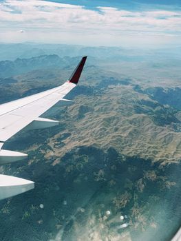 A scenic aerial view from an airplane wing over mountainous terrain on a clear day.