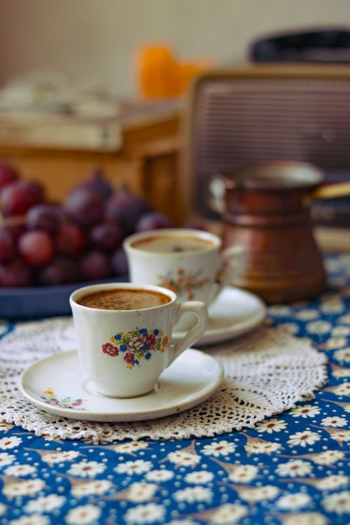 Free Warm cups of Turkish coffee with grapes and a vintage radio on a floral table setting. Stock Photo