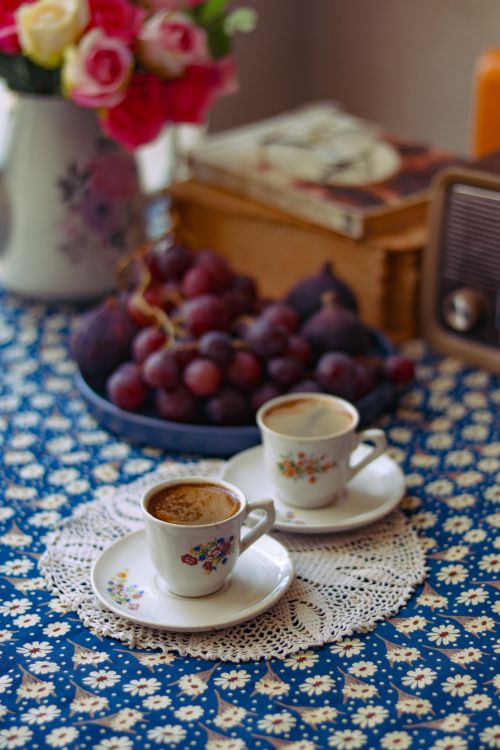 Free Cozy vintage setup with two coffee cups, grapes, and floral decor on a table. Stock Photo
