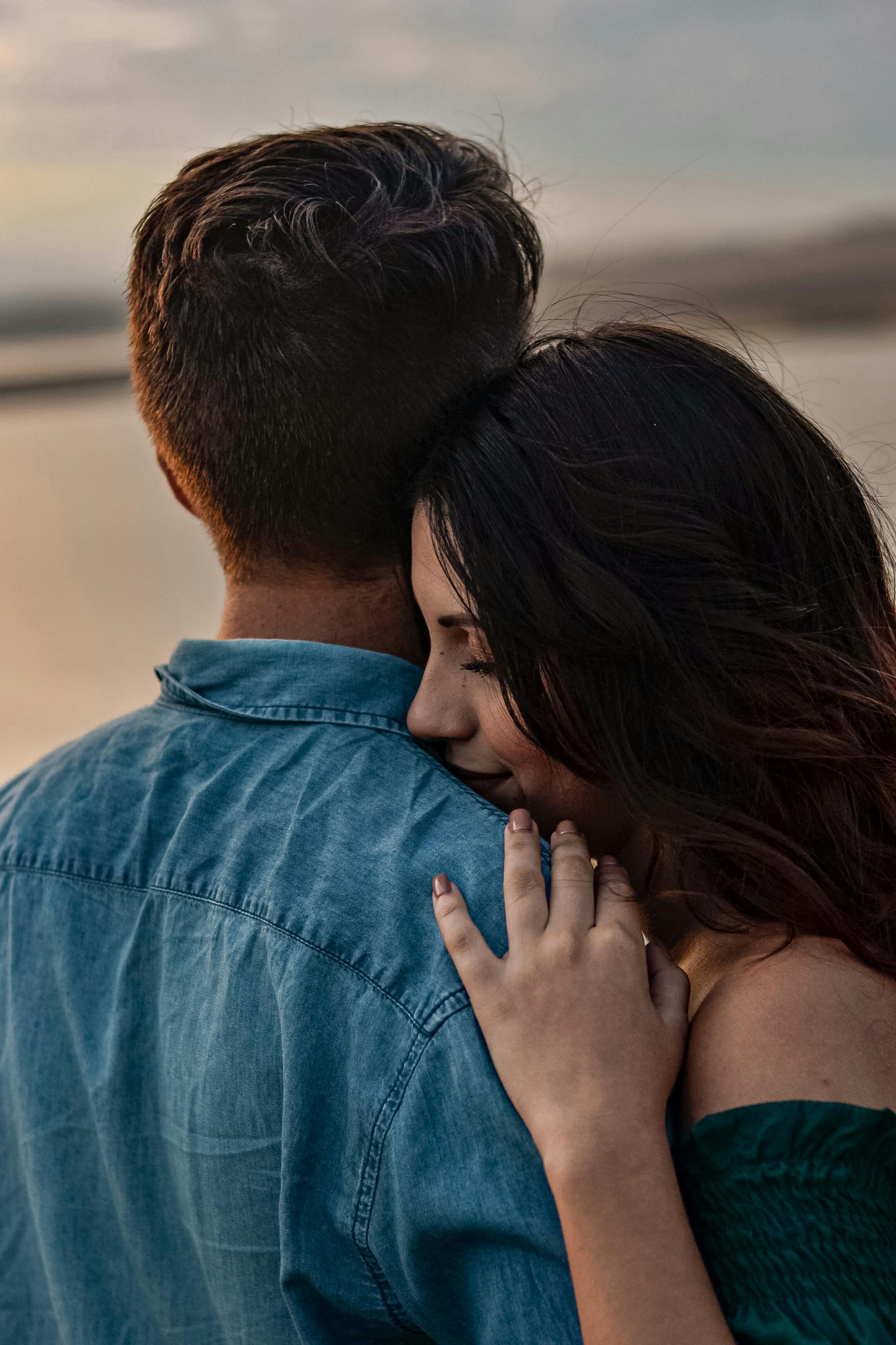 A couple shares a romantic embrace at sunset on a Brazilian beach, exuding warmth and affection.