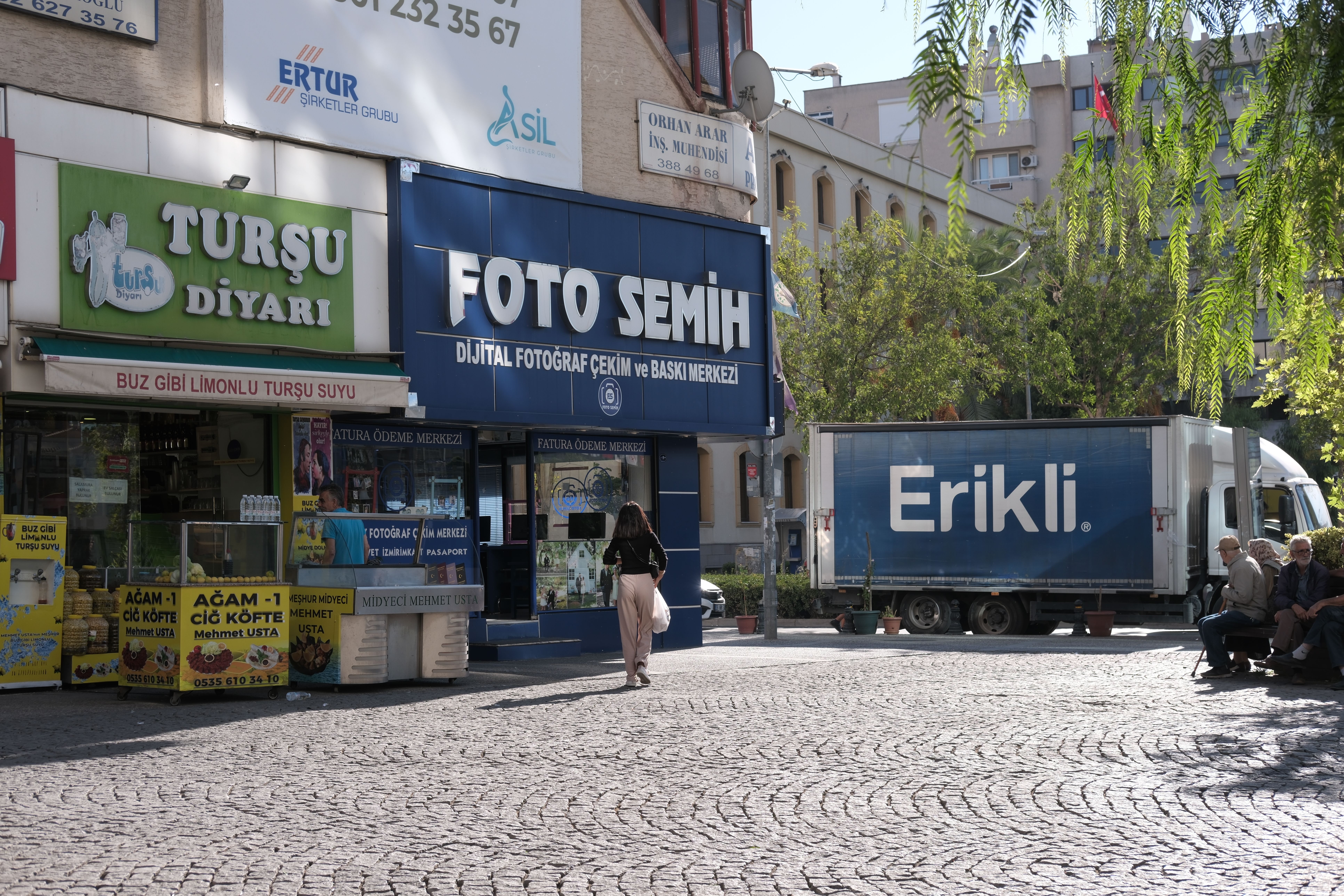 Street view of Bornova, İzmir with local shops and people on a sunny day.
