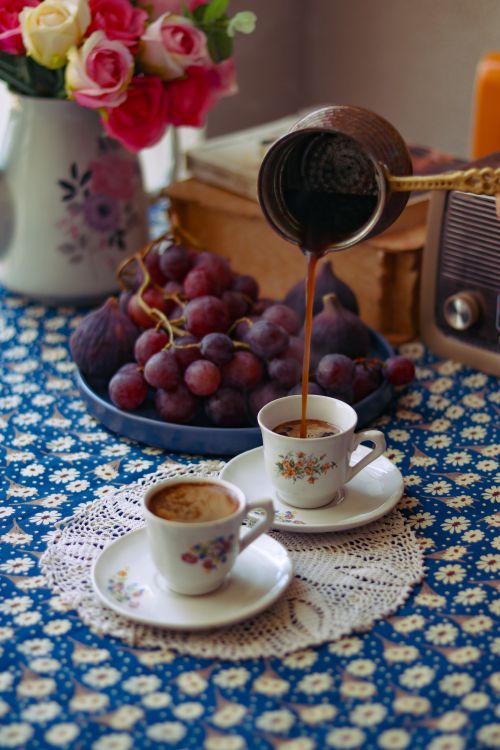 Free Turkish coffee being poured with grapes and flowers on a vintage tablecloth. Stock Photo