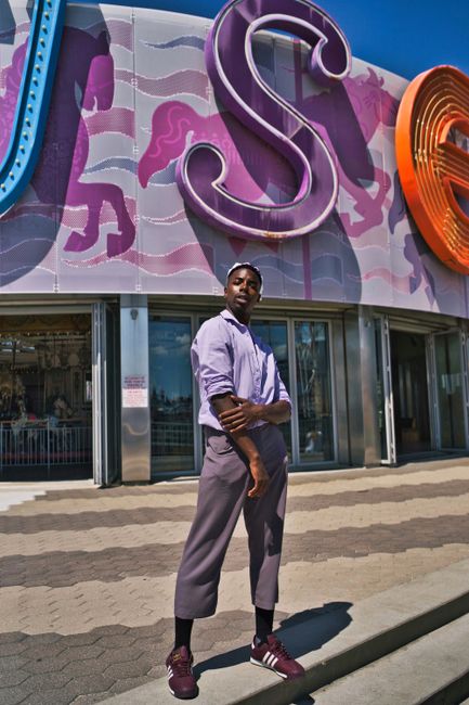 Fashionable man posing outdoors against vibrant carousel backdrop in NYC.