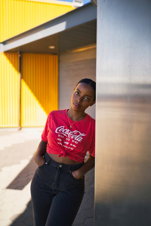 Photo of Woman With Both Hands on Her Pockets Leaning on Metal Wall Panel Posing