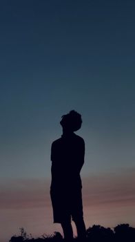 Silhouette of a person against a vibrant twilight sky, suggesting introspection.