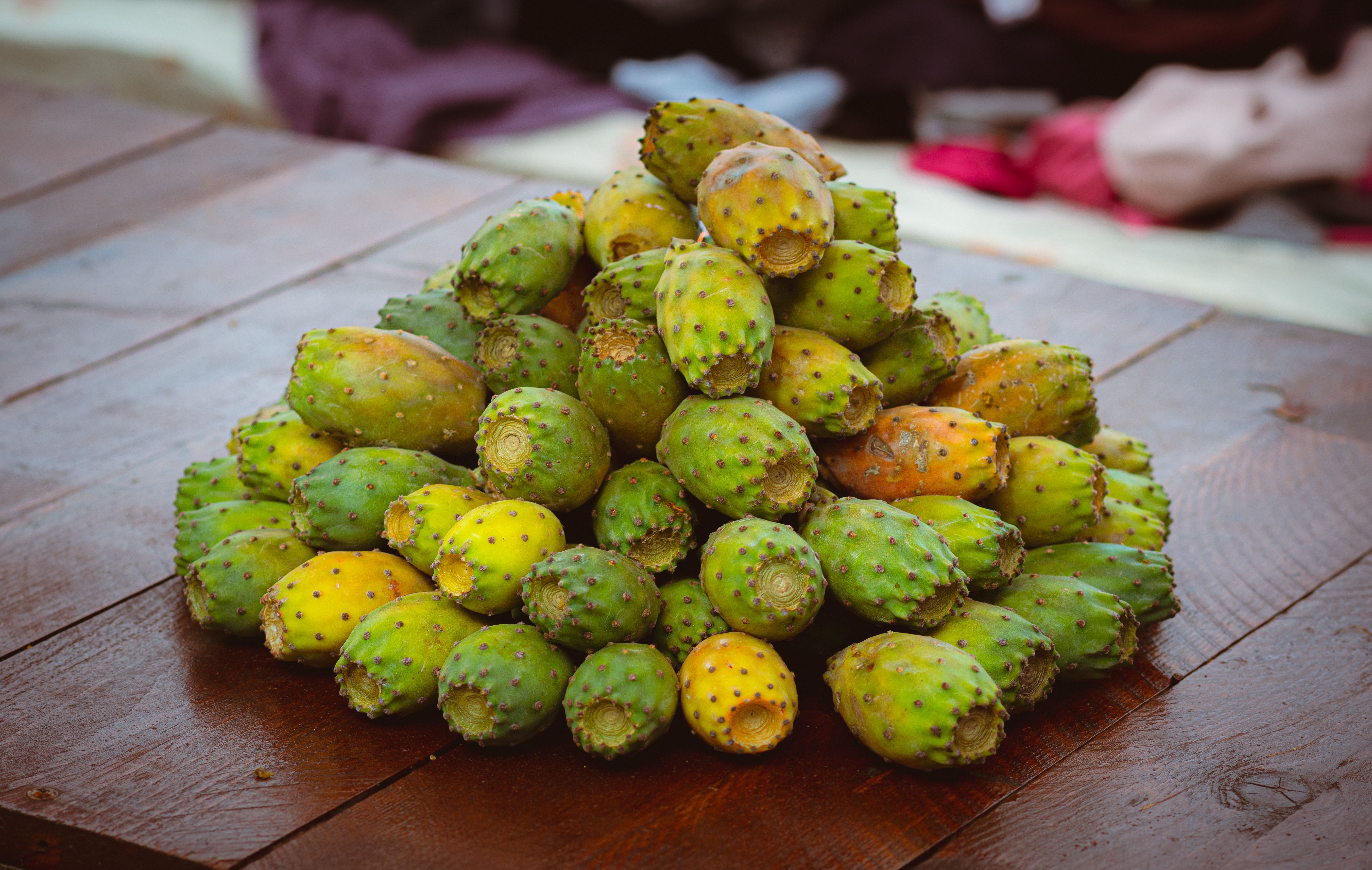A vibrant display of prickly pears stacked on a wooden market table in Tabarka, Tunisia.