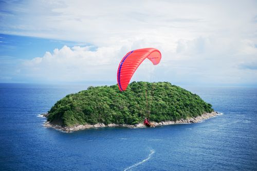 Free Experience an exhilarating paragliding adventure over lush Phuket island and clear blue waters. Stock Photo
