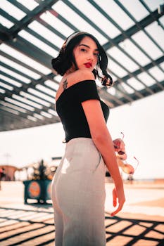 一位优雅的女人，红唇明艳，手持太阳镜，在户外以引人注目的时尚姿态摆拍