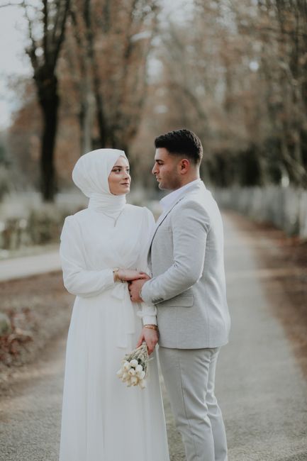 Couple in traditional attire embracing on a tree-lined path in autumn.