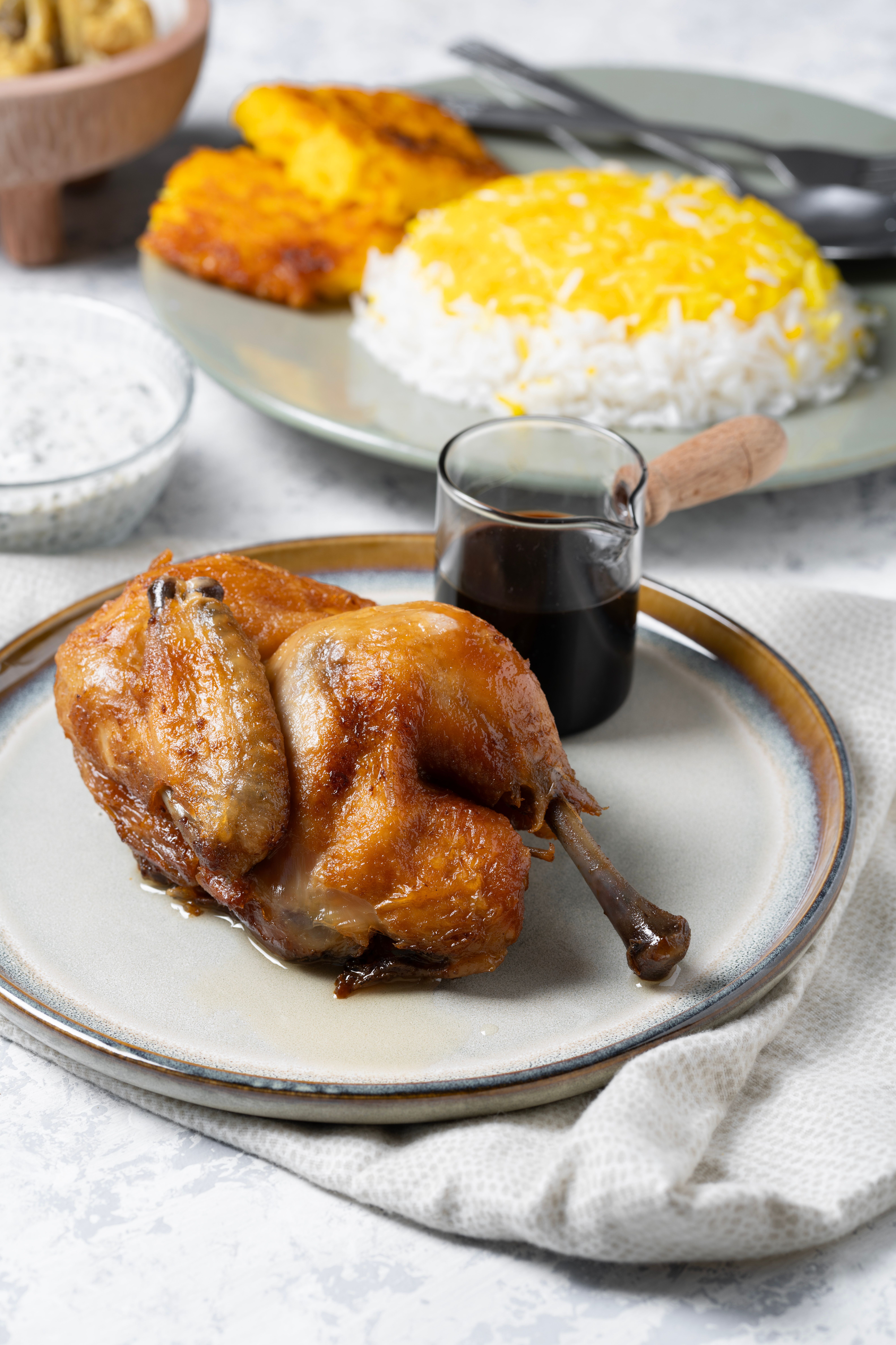 Perfectly roasted chicken served with Persian rice, saffron, and a side of sauce.