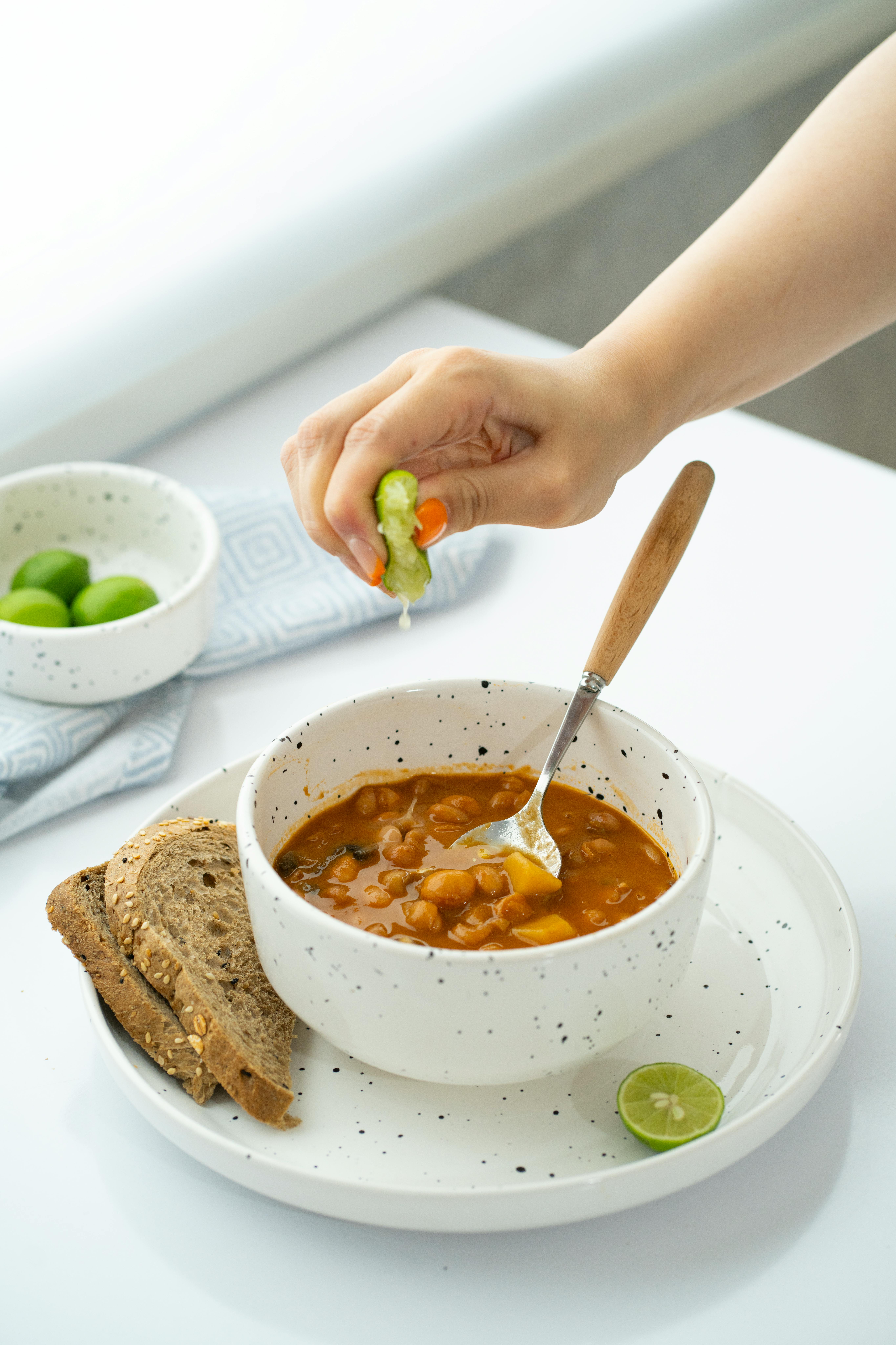 Delicious bean soup with lime squeeze and bread for a cozy meal.