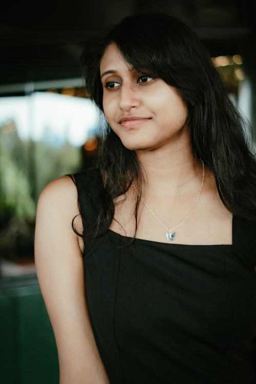 Free A thoughtful woman in a black dress with a necklace, posing indoors, captured during the day. Stock Photo