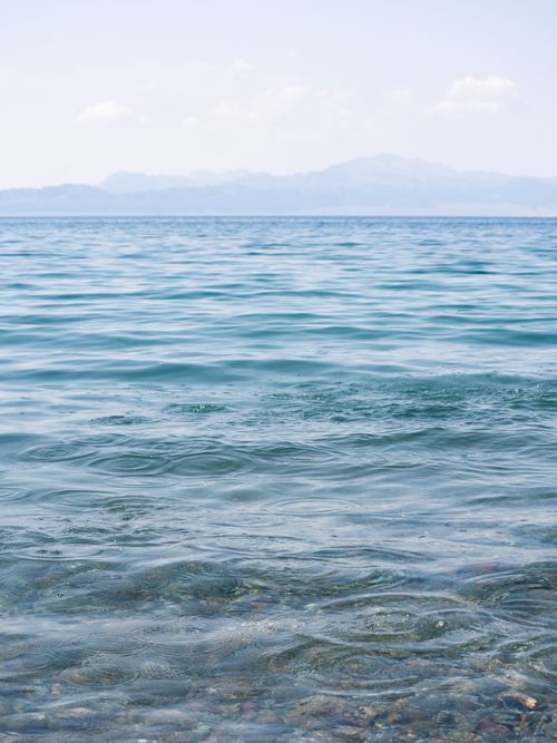 Free Peaceful view of a mountain lake with gentle ripples on the water's surface under a clear sky. Stock Photo