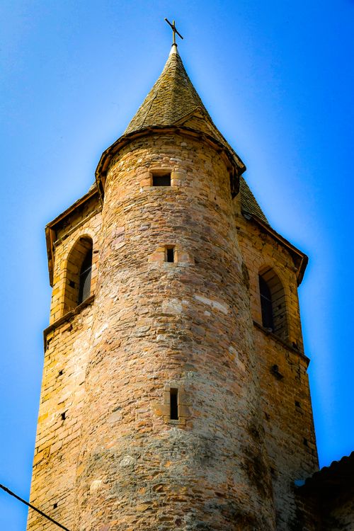 Free A medieval stone tower with pointed roof against a vibrant blue sky. Stock Photo