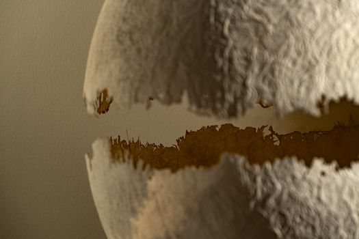 Artistic close-up of worn paper sphere creating an abstract pattern with light and shadow.