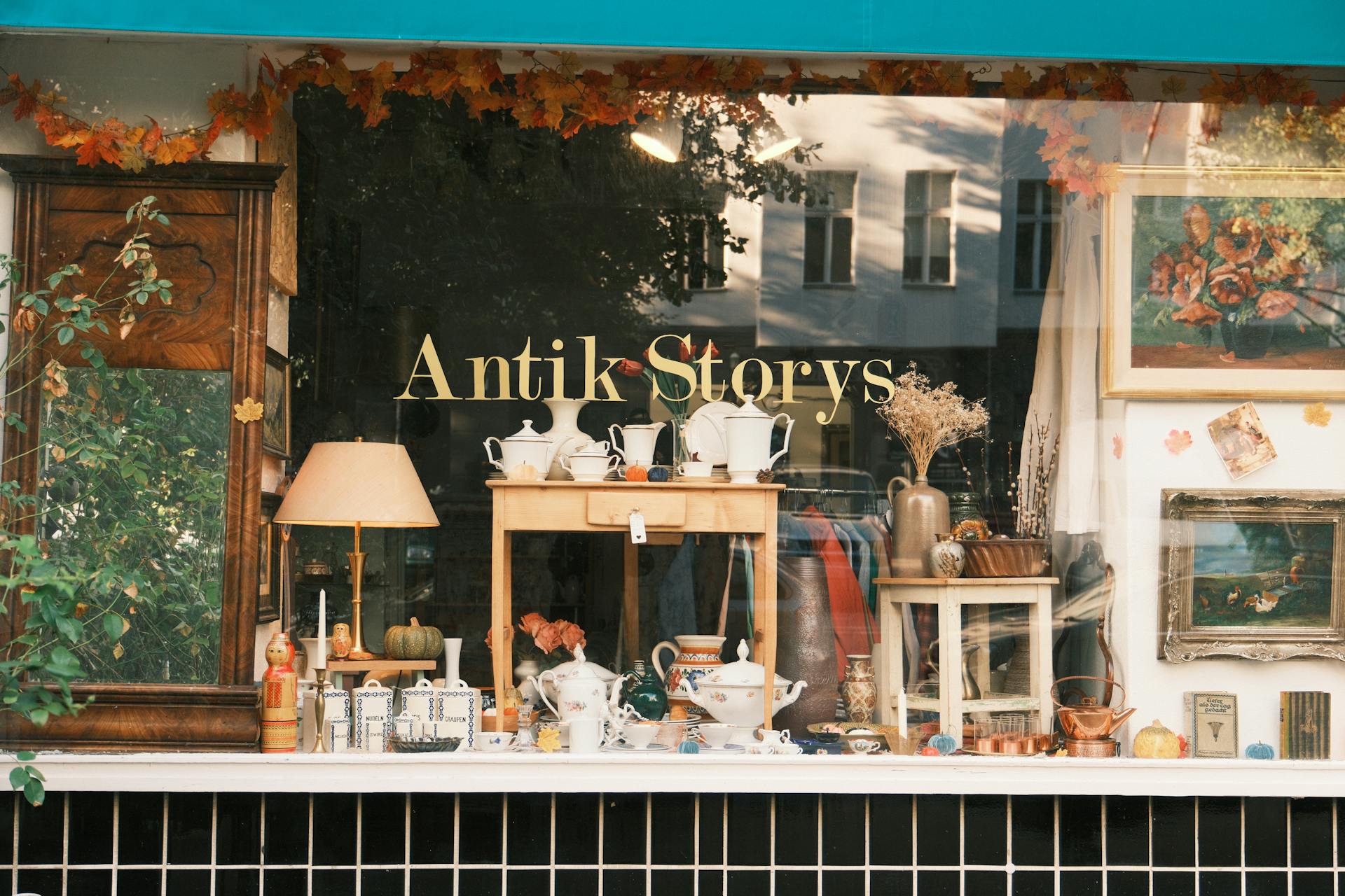 Charming vintage store window showcasing antiques and collectibles in an autumn setting.