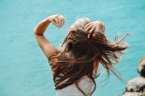 Achteraanzicht Foto Van Vrouw In Wit Mouwloos Shirt Met Haar Vingers Door Haar Haar