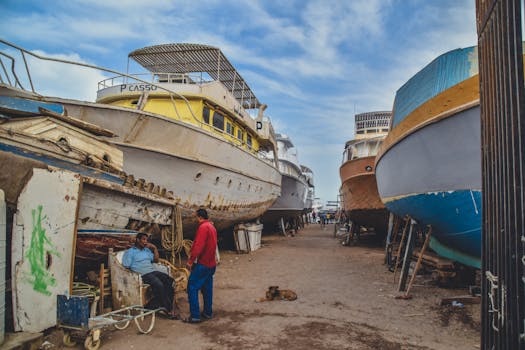 Docked boats in a repair yard in Hurghada, Egypt. Industrial maritime scene with people. by Lian Rodriguez