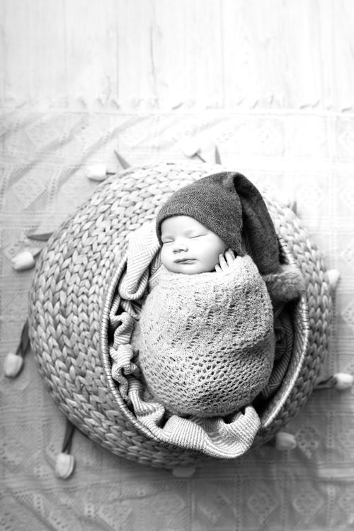 Free A serene black and white portrait of a newborn wrapped snugly in a cozy knit blanket. Stock Photo