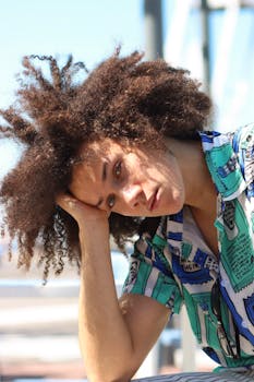 一位卷发时尚男子身着充满活力的服装，在户外摆出休闲风格的姿势