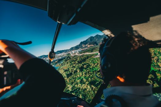 View from helicopter cockpit over Rio de Janeiro with lush landscape and mountains.