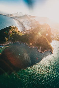 从空中俯瞰里约热内卢海岸线，阳光照耀下的山脉与海洋景色令人惊叹