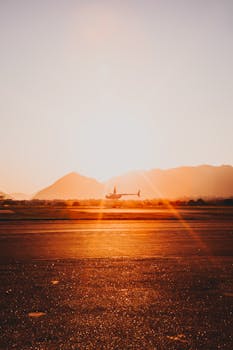 Silhouette of a helicopter flying over a runway at sunset in Rio de Janeiro.