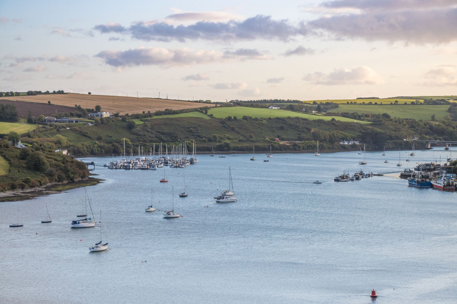 View of boats anchored in Kinsale Harbor, Ireland, under a cloudy sky