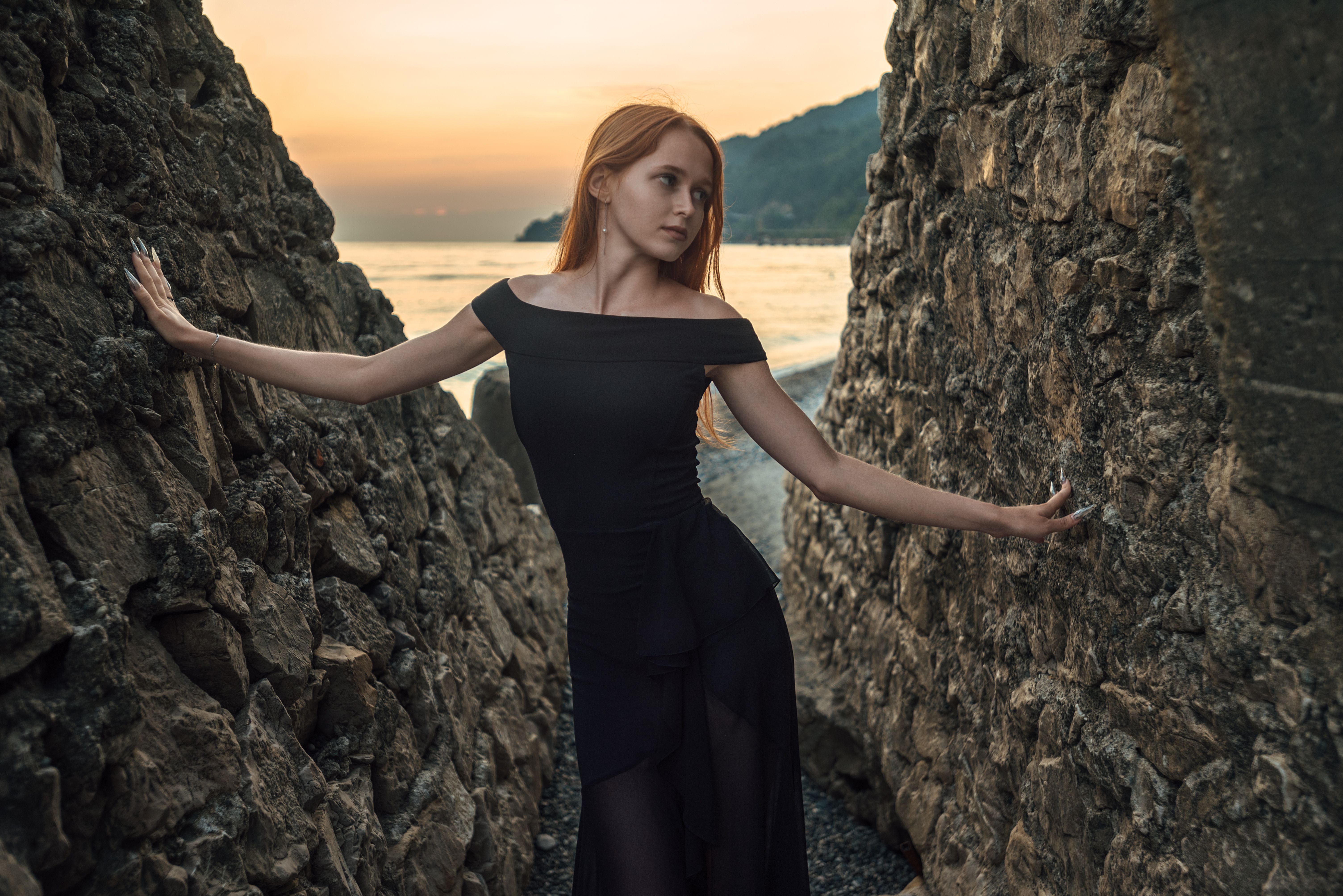 Elegant Woman Posing by Rugged Beach Rocks at Sunset · Free Stock Photo
