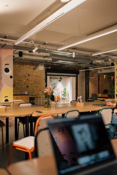 A modern indoor workspace with wooden tables, vibrant decor, and a relaxed atmosphere in London.