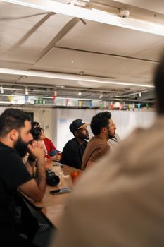 A group of diverse adults attentively participating in a meeting in a modern office setting in London.
