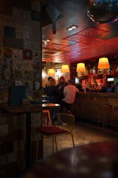 Intimate London bar scene with warm lighting and people enjoying cocktails.
